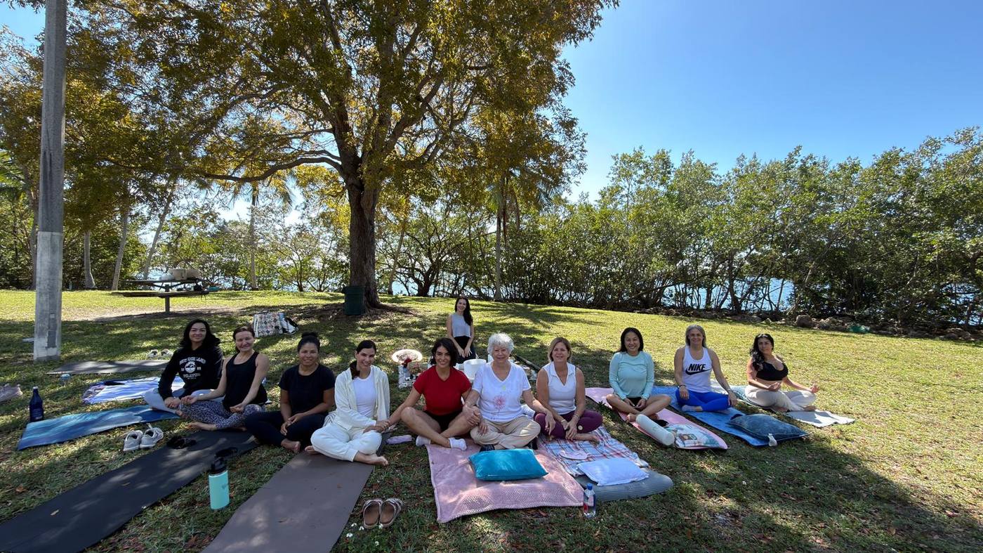A group resting on mats under the trees during an outdoor sound ceremony