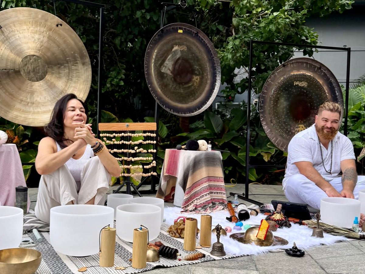 Karina laughing and Juan smiling at the gongs before a session